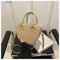 Detalle de bolso beige con forma de corazón y textura de cocodrilo en silla negra - Caqui