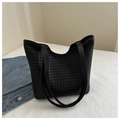 Primer plano de un bolso tote trenzado negro con asas de cuero liso sobre un fondo blanco - Negro