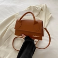 Minimalist brown crossbody bag with gold logo on beige blazer with sleek retro design - Brown