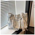 Detalle de bolso tote de lona floral con correa ancha para el hombro y cadena plateada - Azul