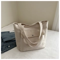 Detail of minimalist cream canvas tote bag featuring a front pocket with a metal snap button - White