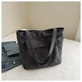 Macro shot of dark grey canvas tote bag with magnetic flap pocket on a soft white bed - Gray