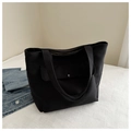 Detail of minimalist black canvas tote bag showing front pocket and silver metal button - Black