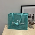 Teal mesh beach bag with white THE BEACH BAG lettering and durable webbing handles - Lake Blue With White Lettering