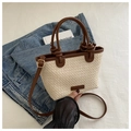 Detail of woven straw tote bag with brown knotted handles and adjustable strap on fabric - Off White