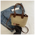 Detail of woven straw tote bag with brown leather handles and a long shoulder strap - Khaki