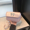 Bolso rosa con lentejuelas y lazo metálico, mostrado en la mano para ver el tamaño - Rosa