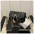 Detail of a black leather handbag with a large sparkling rhinestone bow and silver chain - Black