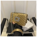 Detailed shot of golden V-quilted handbag featuring a large rectangular rhinestone buckle - Gold