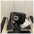 Detail of black V-quilted leather bag featuring large crystal buckle and silver chain strap - Black
