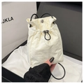 Detail of white nylon drawstring bucket bag with black handles and silver cord lock - White