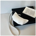 Close-up of white croissant shoulder bag with segmented stitching on a black box - White