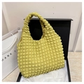 Dettaglio di una borsa gialla con trama a bolle posta in una scatola regalo nera - Giallo