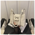 Detail of cream-colored shoulder bag with bow metal buckle and knotted rope handle design - White