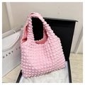 Dettaglio della borsa rosa con trama popcorn presentata in una scatola regalo di lusso - Rosa