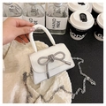 Detail showing the white mini PU leather bag with large rhinestone bow and silver chain strap - White