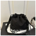 Detail of black nylon bucket bag with drawstring closure and fashion tag on side - Black