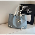 Dettaglio borsa shopper azzurra con borchie a cuore e fiocchi bianchi decorativi - Blu