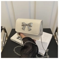 Dettaglio mini borsa bianco crema con fiocco argentato e tracolla a catena - Bianco