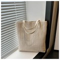Macro shot of V-shaped weaving texture and beige leather straps on straw tote bag - Off White