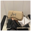 Detalle de bolso beige con borde ondulado y decoración de lazo metálico plateado - Caqui