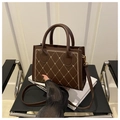 Deep brown quilted crossbody bag with embroidery and golden stitching on white prop - Coffee