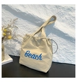Details der beigen Nylon-Kordelzugtasche mit blauem Beach-Text und Kordelverschluss - Gelb