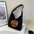 Minimalist black canvas tote bag with brown leather letter patch and wide shoulder strap - Black