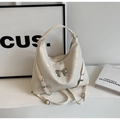 Detail of white pearlescent tote bag featuring silver metal bow and decorative side straps - Off White