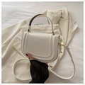 Dettaglio borsa a sella bianca con cuciture a U e finiture dorate su un blazer crema - Bianco