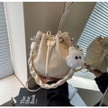 Detalle del bolso tipo cubo de paja beige con cordón, textura ondulada y colgante de peluche - Blanco (Con Colgante)