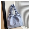 Dettaglio della borsa a secchiello in nylon azzurro con borchie e manico a pieghe - Blu