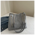 Detailed view of the embossed Fashion text on a grey tote bag with gold chain strap - Silver
