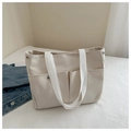 Detail der cremefarbenen Canvas-Tasche mit Vordertaschen und Metallnieten-Verstärkung - Weiß