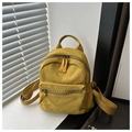 Dettaglio di un mini zaino in tela giallo zenzero con tasca frontale con zip su scaffale bianco - Giallo