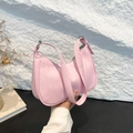 Pink crescent shoulder bag with quilted texture and adjustable strap in a lifestyle setting - Pink