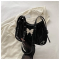 Close-up of black ruched shoulder bag with silver butterfly charm and eyelet strap - Black