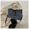 Close-up of denim shoulder bag with white polka dots, brown leather flap and silver chain - Blue