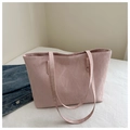 Detail of pink tote bag with pleated texture shown alongside a blue denim jacket - Pink