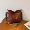 Brown vintage leather bucket bag with bohemian wide shoulder strap on wooden desk - Brown