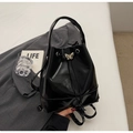 Detail of black glossy bucket bag featuring silver butterfly buckle and drawstring closure - Black