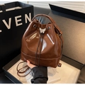 Detail of a brown glossy bucket bag with drawstring closure and white bow buckle - Brown
