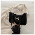 Retro black leather underarm bag featuring a golden metal bow on a beige blazer - Black
