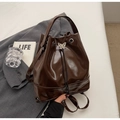 Dark brown glossy bucket backpack with a vintage butterfly drawstring lock detail - Coffee