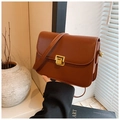 Caramel brown vintage shoulder bag with golden buckle shown held by a model - Brown