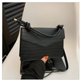 Sac à main noir à motif crocodile avec poignée nouée et rabat sur une chaise blanche - Noir