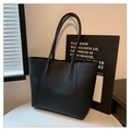 Bolso tote clásico negro con acabado texturizado sobre una mesa blanca minimalista - Negro