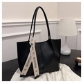 Detail of a large black leather tote bag with a cream fashion ribbon on white background - Black