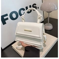 Detalle del bolso blanco crema con asa anudada y cierre de metal dorado - Blanco