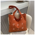 Caramel orange corduroy tote bag with white MY FUTURE embroidery on a stylish chair - Orange